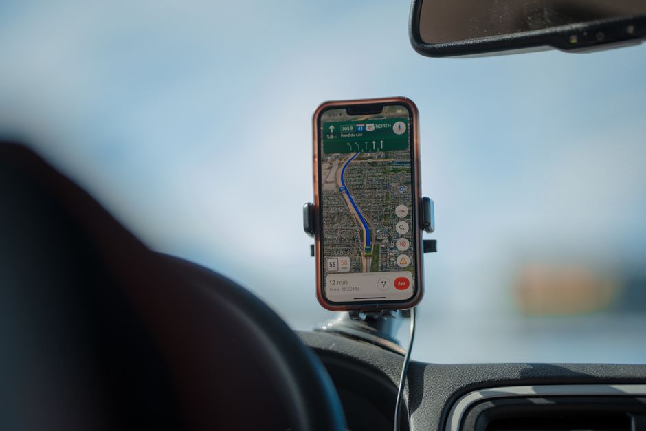 Des voyageurs consultent une application de navigation sur smartphone dans une voiture chargée