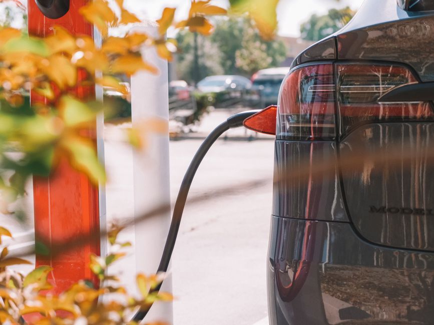 Acheteur inspectant la batterie et le câble de recharge d'une voiture électrique d'occasion